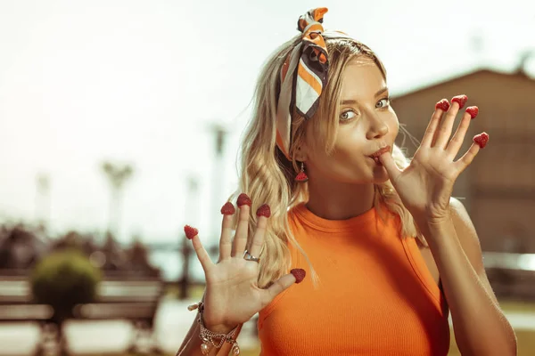 손가락에 딸기와 함께 포즈를 취하는 젊은 여성의 얼굴 초상화. — 스톡 사진