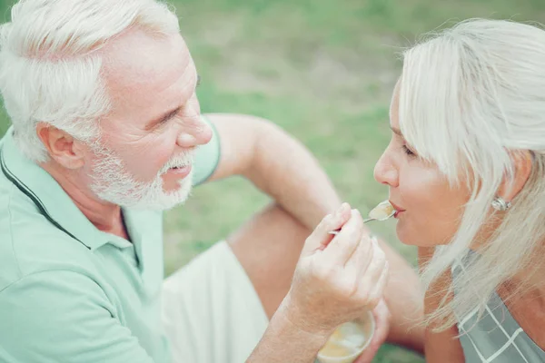 Sevgili karısını besleyen neşeli yaşlı adam — Stok fotoğraf
