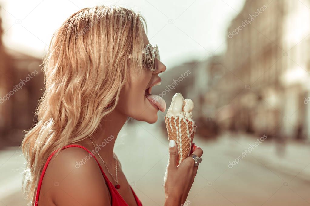 Close-up profile portrait of beautiful female leaking melting tasty ice-cream
