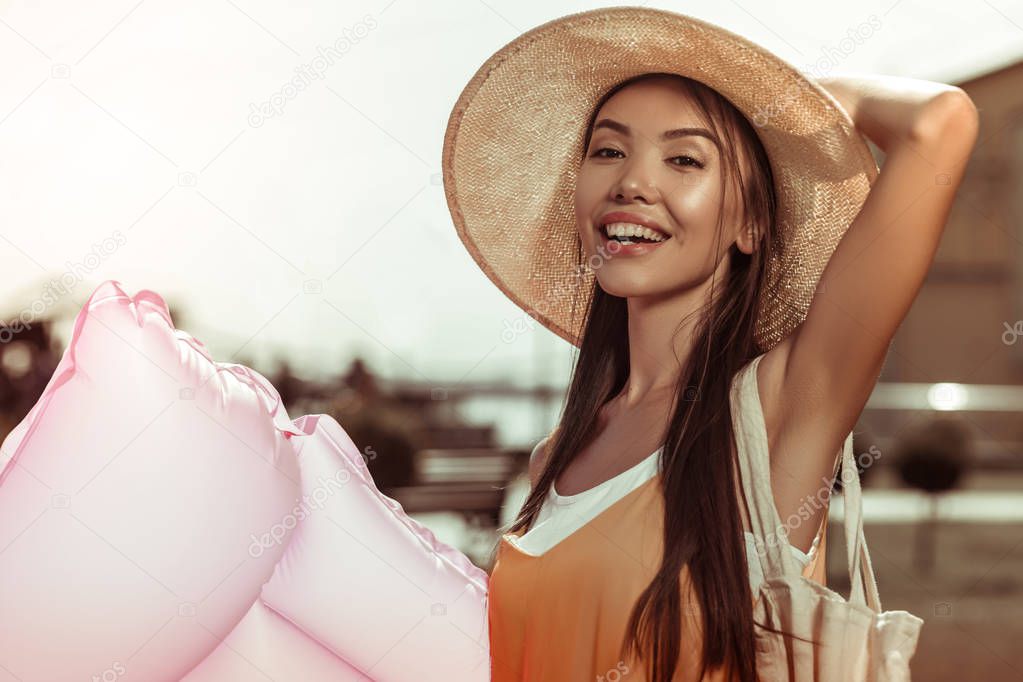 Face-portrait of female wearing straw hat and holding air mattress