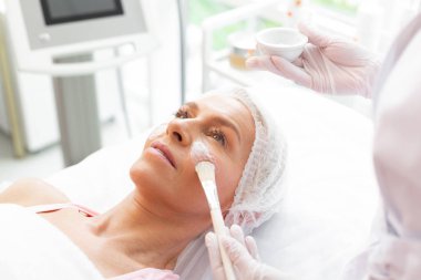 Yüz maskesi uygulanan güzel yaşlı kadın