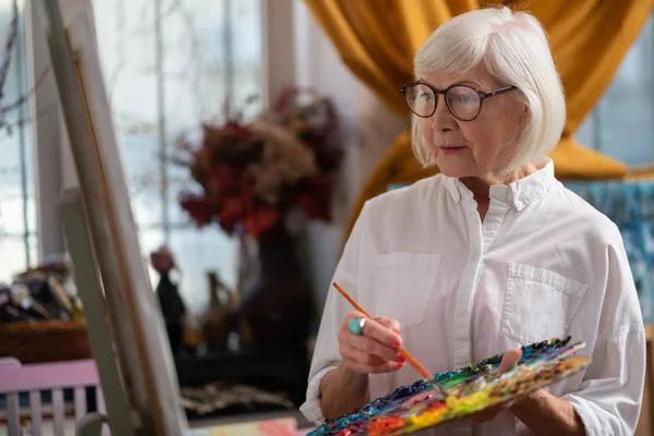 Mujer con gafas sosteniendo paleta de colores y pincel —  Fotos de Stock