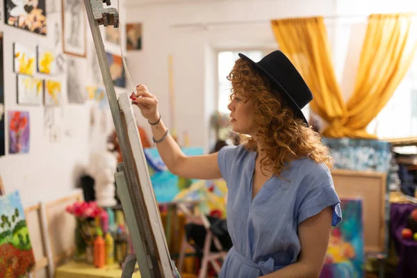 Talented young artist wearing blue dress painting on canvas — Stock Photo, Image