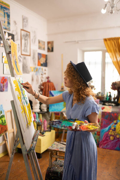 Стройная молодая художница в восторге от раскрашивания картины
