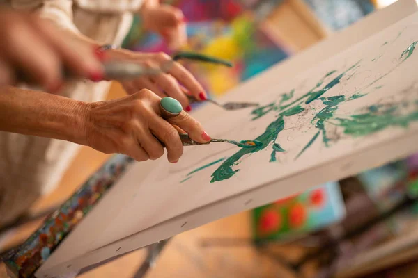 Artista sosteniendo paleta de pintura con gouache mientras colorea la imagen — Foto de Stock