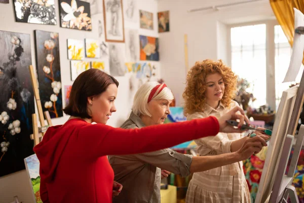 Artista envelhecida colorir imagem com seus dois jovens estudantes — Fotografia de Stock