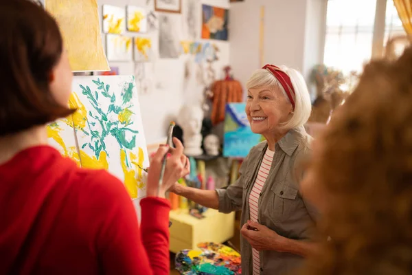 Cheerful retired woman teaching her students to paint — Stock Photo, Image