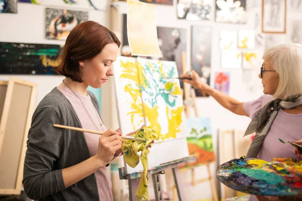 Konststudent torkning hennes målning borste efter grön gouache — Stockfoto