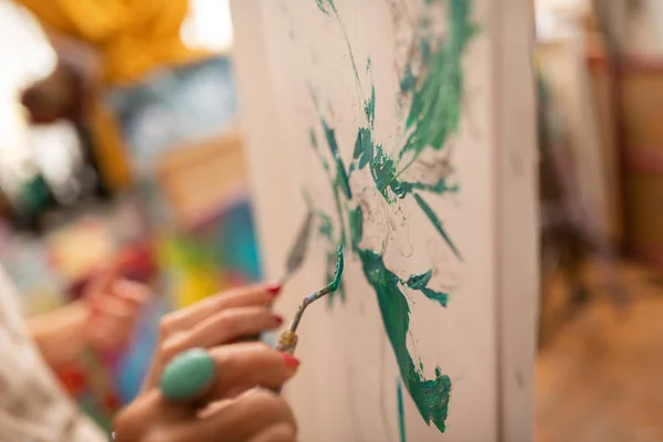 Художник в массивной кольцевой раскраске с зелеными гуашами — стоковое фото