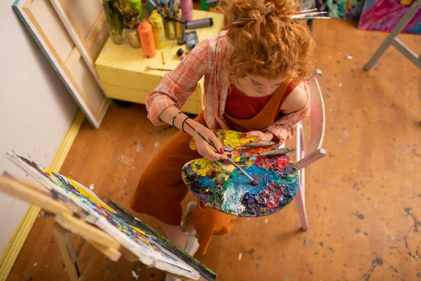 Vista superior de artista con pelo latón celebración de la paleta de colores —  Fotos de Stock