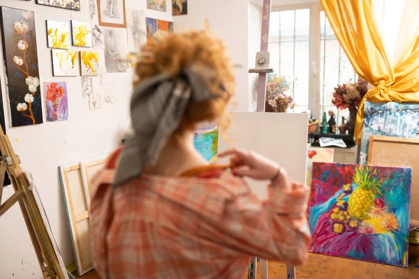 Rödhårig konstnär stående nära vit canvas och fönster — Stockfoto