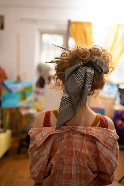 Artista con moño de pelo con pinceles en el pelo — Foto de Stock