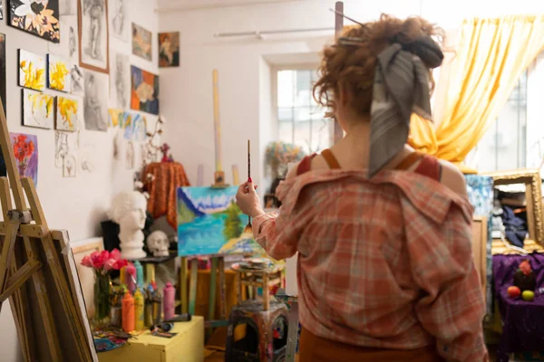 Red-haired artist with hair bun holding painting brush — Stock Photo, Image