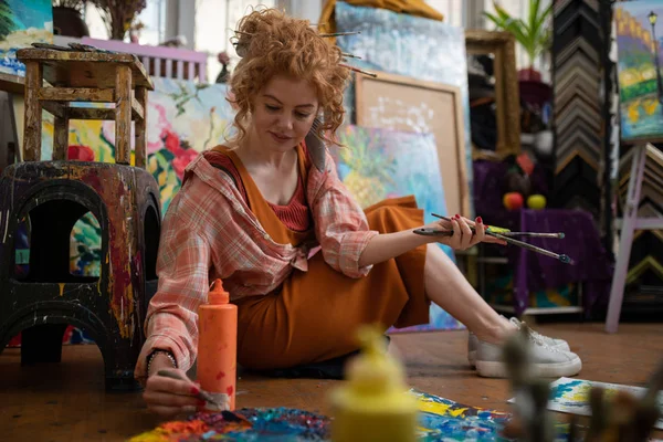 Curly estudante de arte ter ideias de pintura sentado no chão — Fotografia de Stock