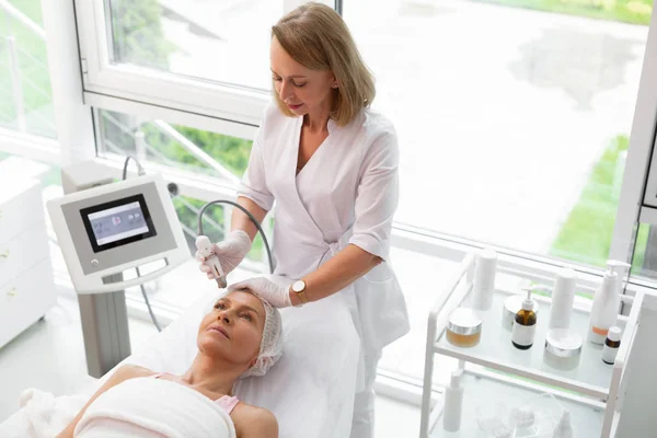 Professional skilled doctor cleansing her clients face — Stock Photo, Image