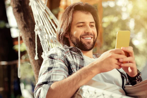 Vrolijke knappe man kijkt naar zijn smartphone scherm — Stockfoto