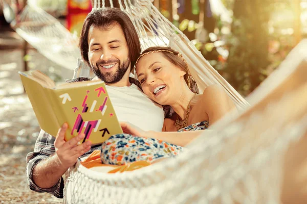 Feliz pareja positiva leyendo una historia divertida — Foto de Stock