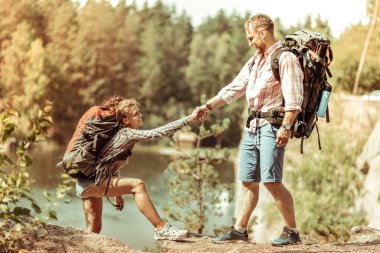 Joyful güzel adam tırmanmaya kız arkadaşı yardım