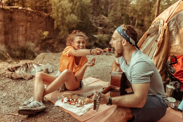 Mujer alegre alegre dando una salchicha a su novio — Foto de Stock