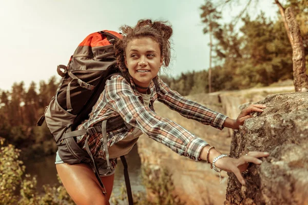 Beautiful curly woman holding on to the cliff — Stock Photo, Image