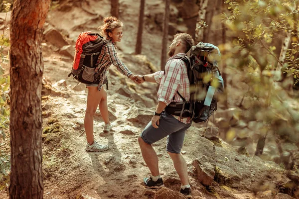 Nice joyful woman supporting her boyfriend during hiking — Stock Photo, Image