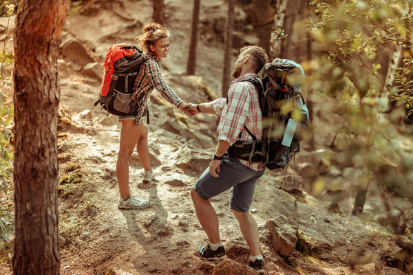 Nice joyful woman supporting her boyfriend during hiking
