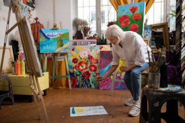 Sanatçı yere kağıt koyarak ve bazı boya serpme