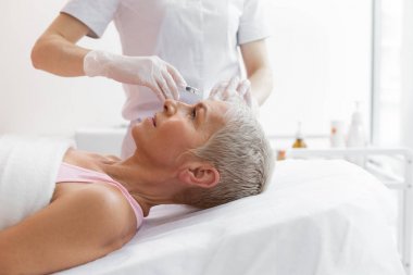 Alnına botoks enjeksiyonu alan güzel gri saçlı kadın