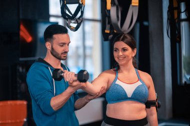 Sakallı eğitmen barbells ile kilolu kadın yardım