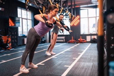 Koyu saçlı kadın Trx üzerinde egzersiz yaparken bitkin hissediyorum