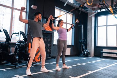 Atletik yakışıklı fitness eğitmeni kadın egzersizleri gösteren