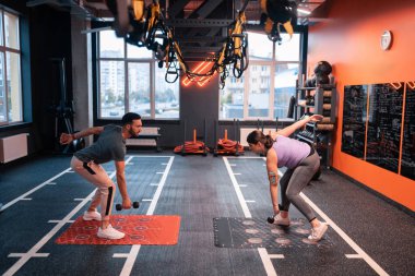 Eğitmen ve kilolu müşteri halter ile egzersiz yapıyor