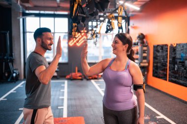 Koyu saçlı tombul kadın onu fitness eğitmeni için yüksek beş veren