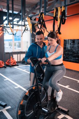 Fitness döngüsünde oturan kadın yardımcı koyu saçlı eğitmen