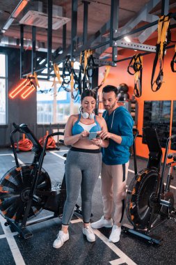 Sakallı fitness eğitmeni müşteri için iyi bir spor uygulaması tavsiye