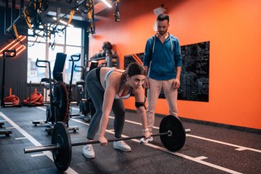 Koyu saçlı tombul kadın ilk kez halter kaldırmaya çalışıyor