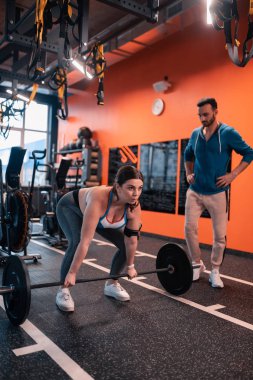 Tombul güçlü kadın eğitmen yanında duran halter kaldırma