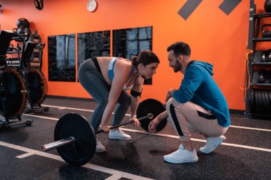 Sakallı eğitmen barbell kaldırmak için onun tombul müşteri motive