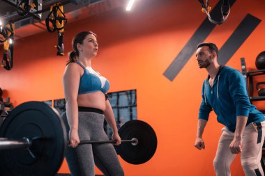 Sakallı koyu saçlı eğitmen barbell kaldırmak için tombul kadın öğretim