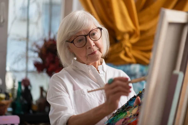 Σκούρα μάτια ηλικίας γυναίκα ζωγραφική στο εργαστήριο νιώθοντας καλά — Φωτογραφία Αρχείου