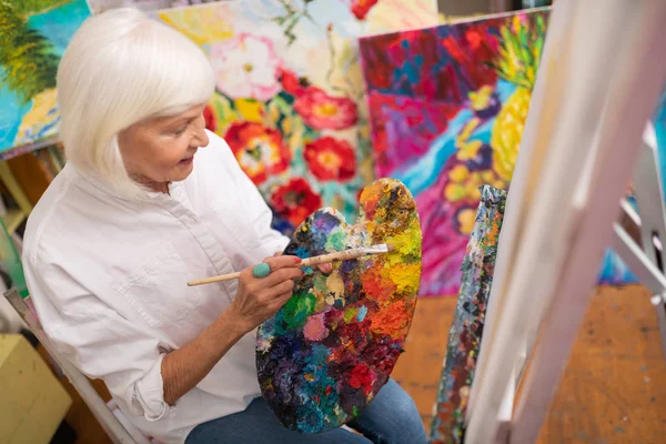 Artysta ubrany w dżinsy i biała bluzka farbowanie jej obraz — Zdjęcie stockowe