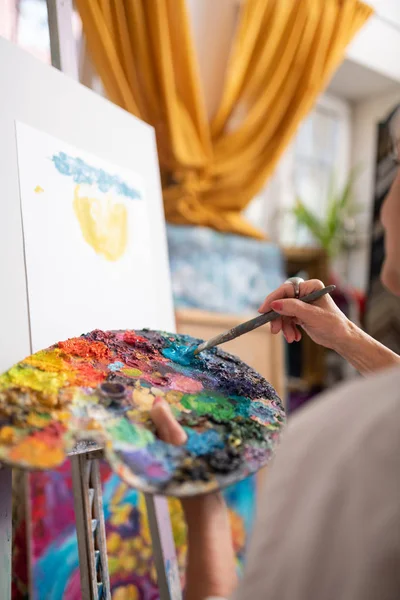 Vrouw met kleurenpalet mengen kleurrijke gouache en schilderen — Stockfoto