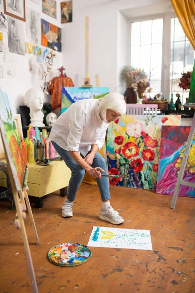 Artiste portant un jean saupoudrant de peinture sur papier — Photo