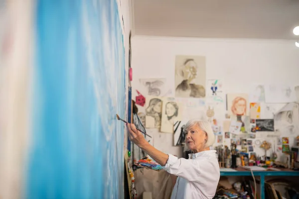 Femme portant une blouse blanche coloriant la toile en couleur bleue — Photo