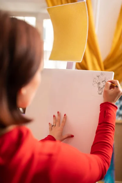 Young artist with red nails drawing on white canvas