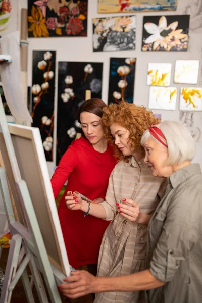 Três mulheres bonitas talentosas pintando na lona juntos — Fotografia de Stock