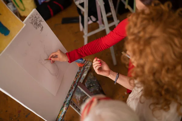Begåvade konstnärer pratar och ritning vas på duk — Stockfoto