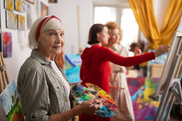 Famous artist standing in workshop near her students