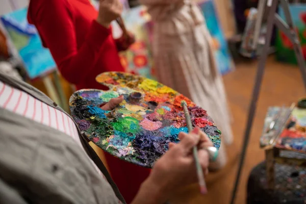 Artista tenendo pennello e mescolando guazzo sulla tavolozza — Foto Stock