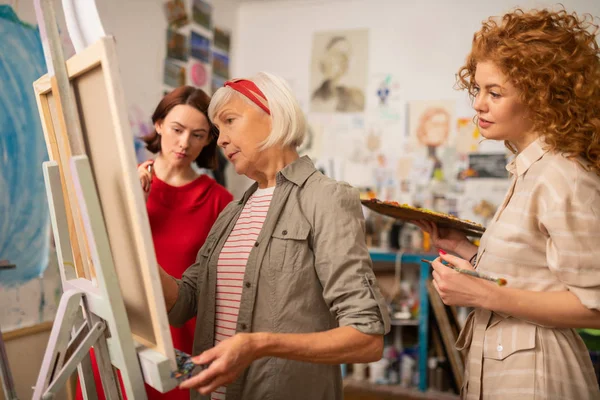 Two young women looking at famous artist painting on canvas